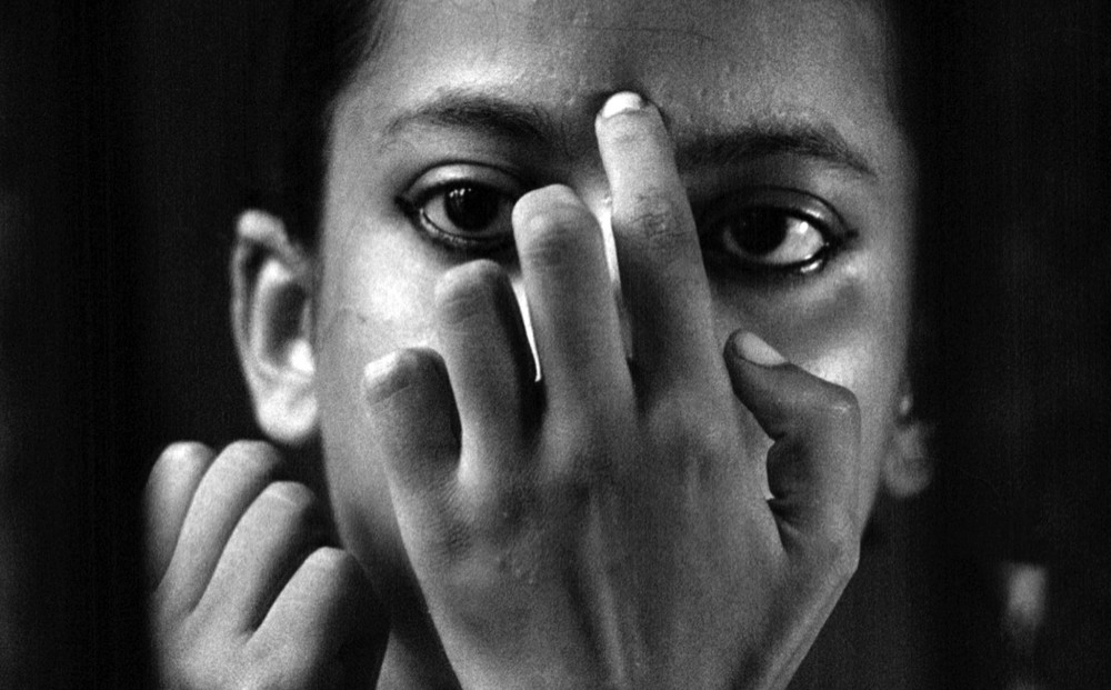 Close-up on actor Uma Das Gupta's face; her hand covering her mouth, cheeks, and nose.