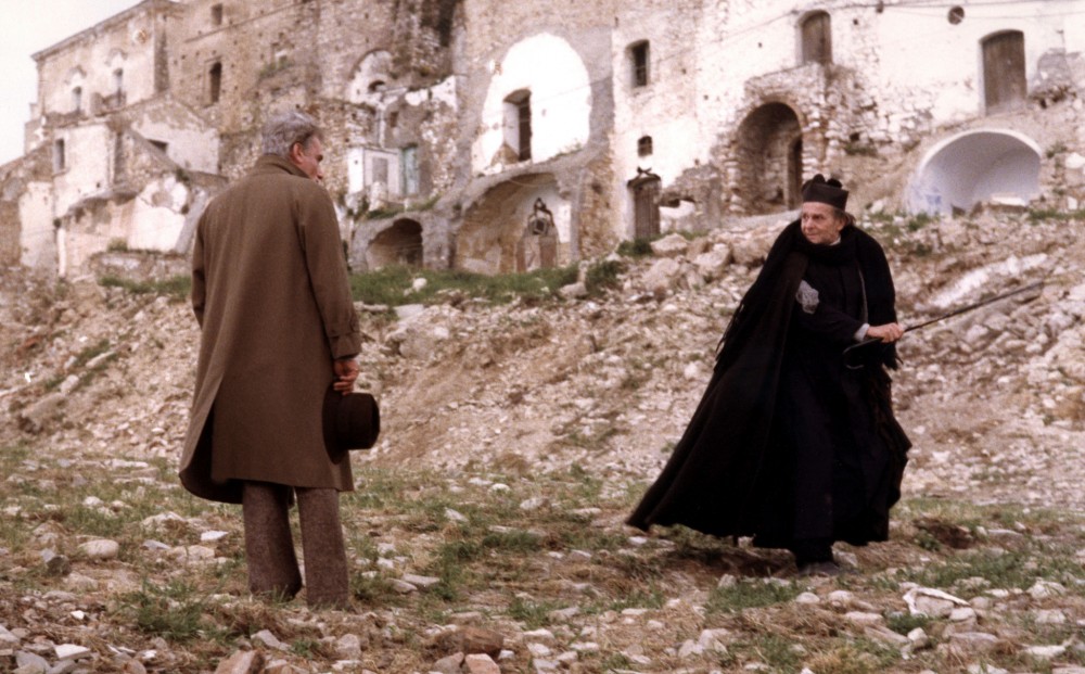 Actor Gian Maria Volontè speaks with a woman near ruins.