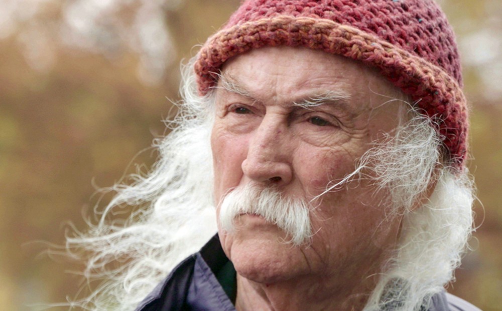 Close-up on the face of musician David Crosby with a white moustache and white hair.