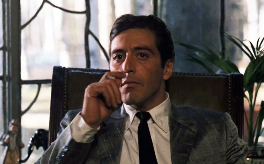 Actor Al Pacino smokes a cigarette while seated.