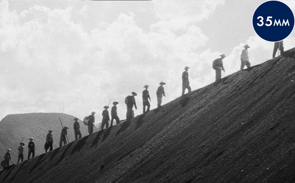 People walking in a line along a barren hillside.