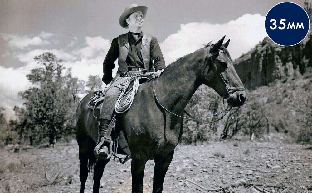 Actor Dick Powell astride a horse.