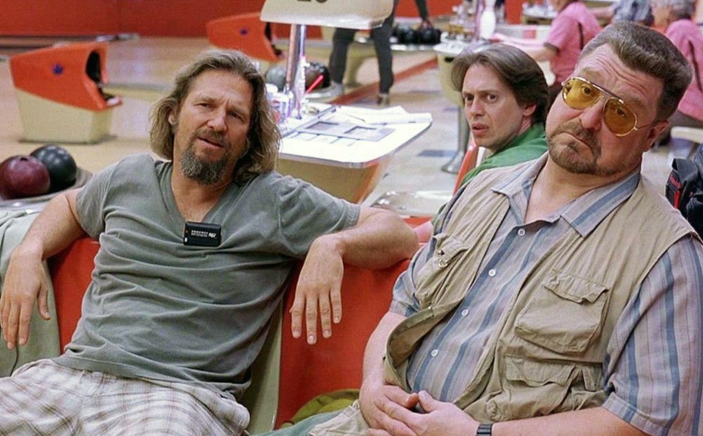 Actors Jeff Bridges, Steve Buscemi, and John Goodman sit at a bowling alley.