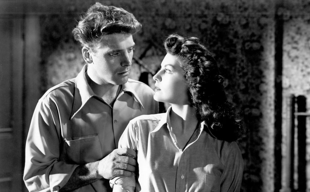 Actors Ava Gardner and Burt Lancaster look at each other; he holds her arm.