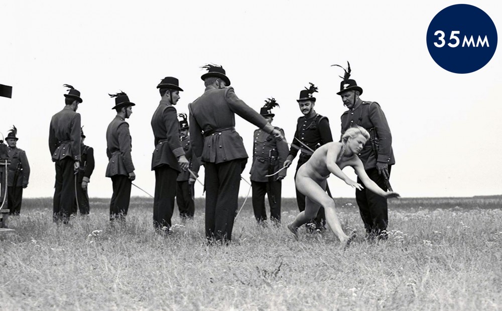 A naked woman falls to the ground between two rows of soldiers in a field.