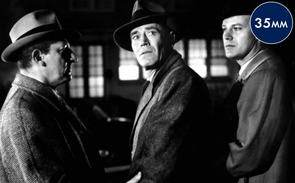 Actor Henry Fonda stands with two other men, one of whom is holding his arm.