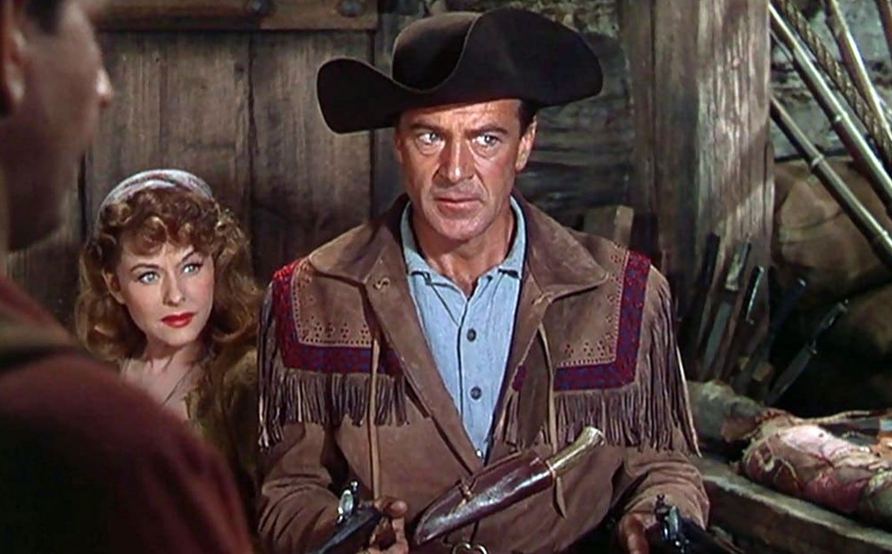 Actor Paulette Goddard stands next to actor Gary Cooper, who wields two guns.