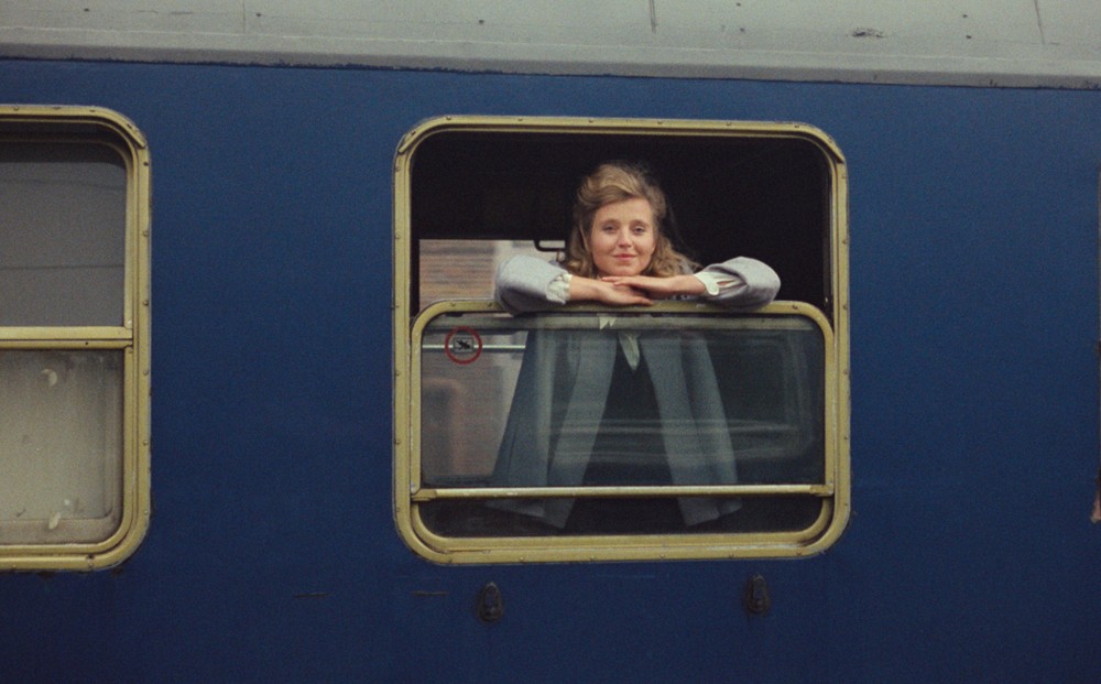 A woman looks out the window of a train car.