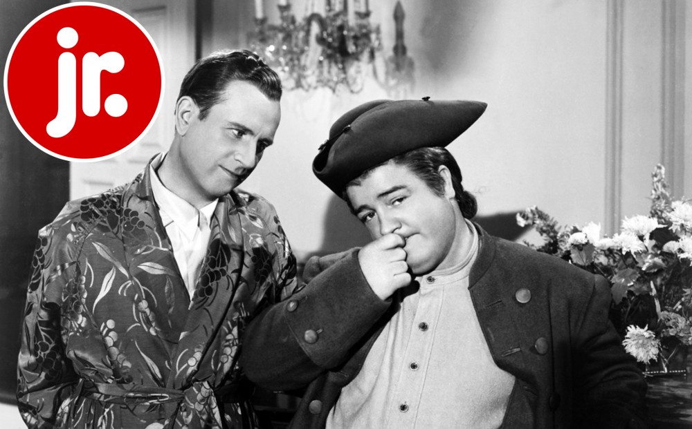 Abbott and Costello stand together, one looking at the other.