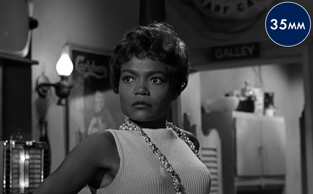 Actor Eartha Kitt stands and looks intently at something off-camera.