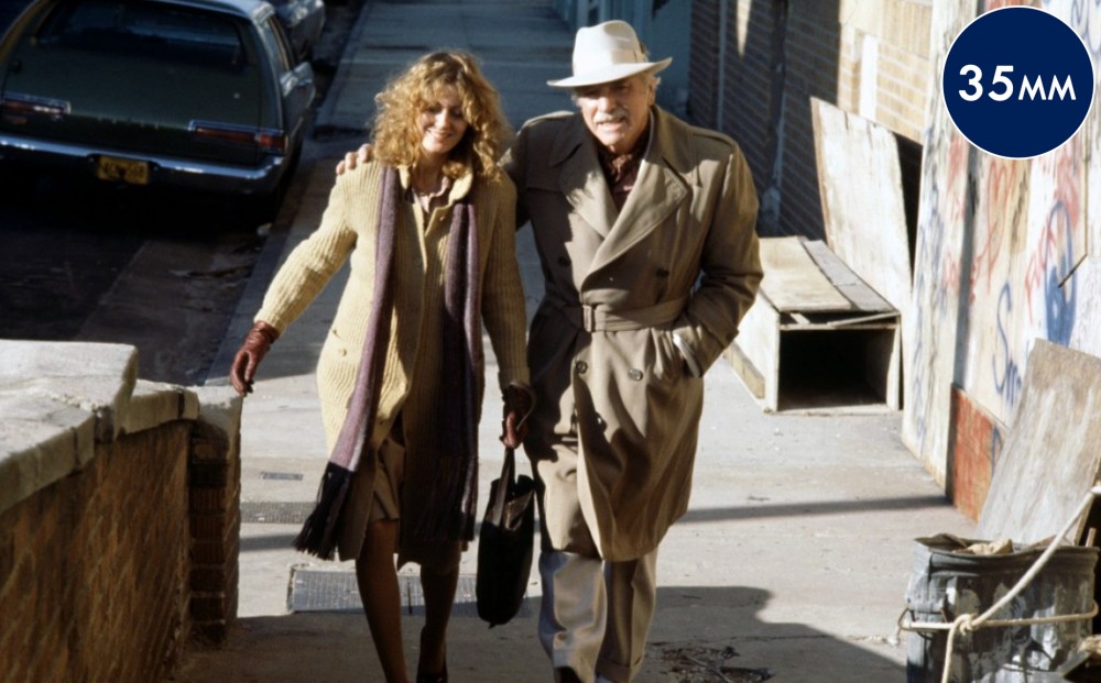 Actors Burt Lancaster and Susan Sarandon walk down the street together, his arm around her shoulder.