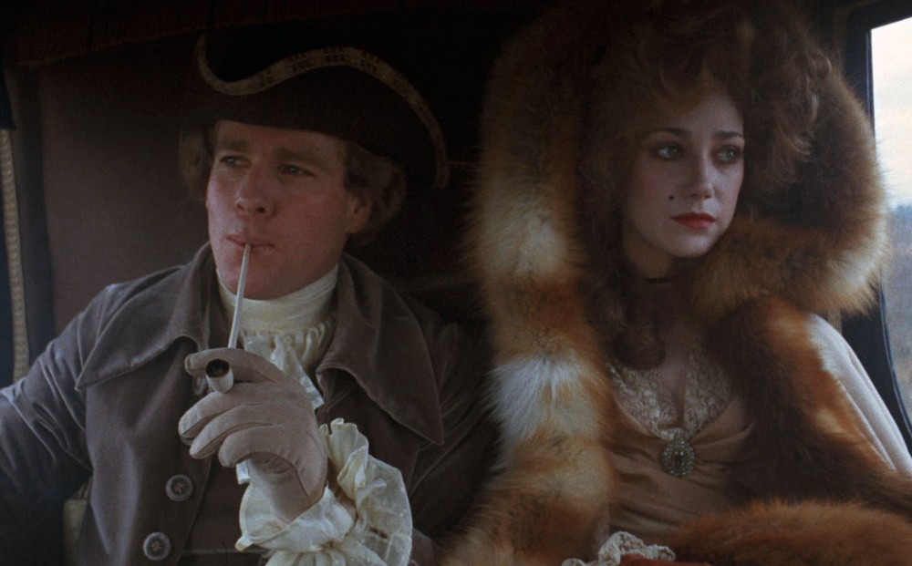 Actor Ryan O'Neal sits in a carriage next to a woman in a fur-lined coat.