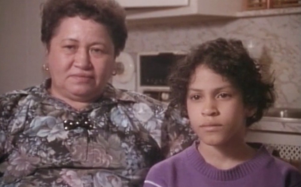 A woman and child sit together, facing the camera.