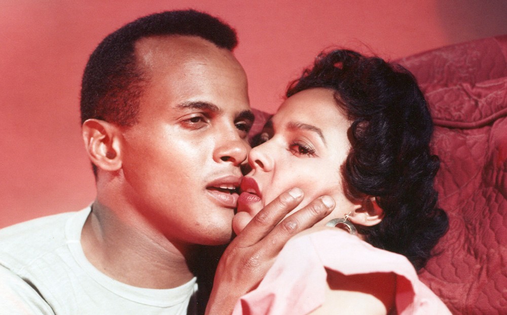 Actors Dorothy Dandridge and Harry Belafonte embrace, their lips touching, but without looking at each other. 