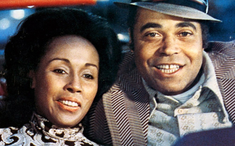 Actors Diahann Carroll and James Earl Jones sit next to each other in a car, looking happy.
