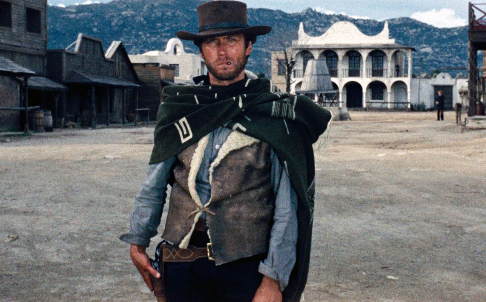 Actor Clint Eastwood stands with his hand poised on his gun holster.