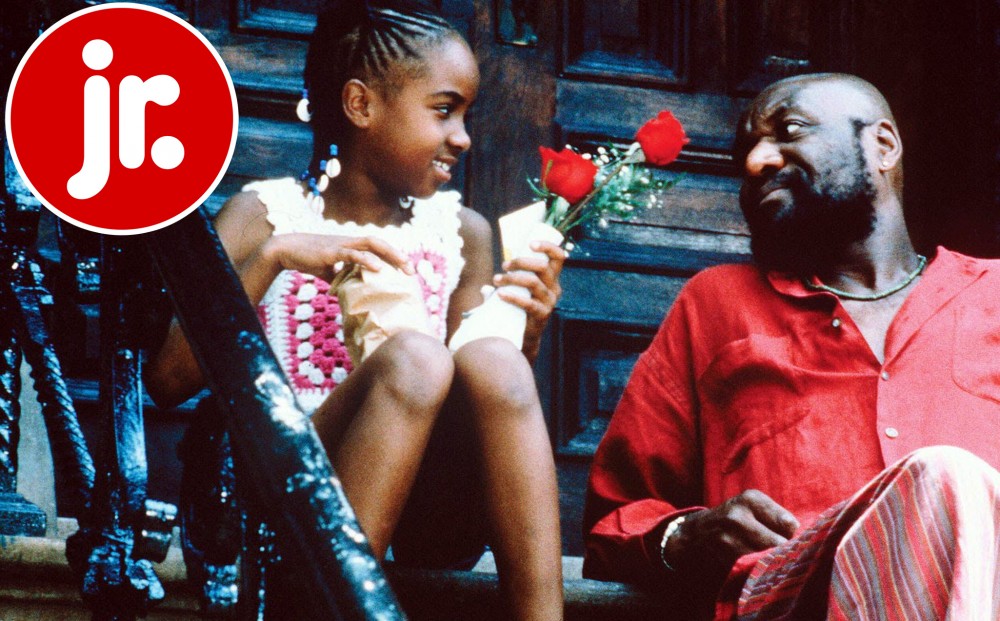 A man sits on a stoop with a young girl, who holds red roses.