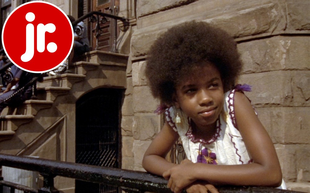 A young girl leans over the gate in front of a Brooklyn brownstone.