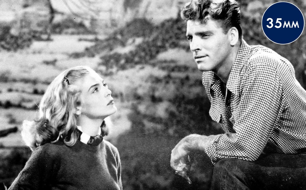 Actor Burt Lancaster gazes off, with his hand on his knee; Lizabeth Scott gazes at him.