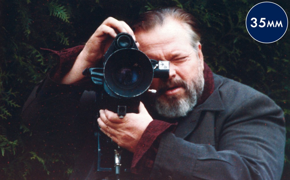 Actor/director Orson Welles holds a camera up to his face.