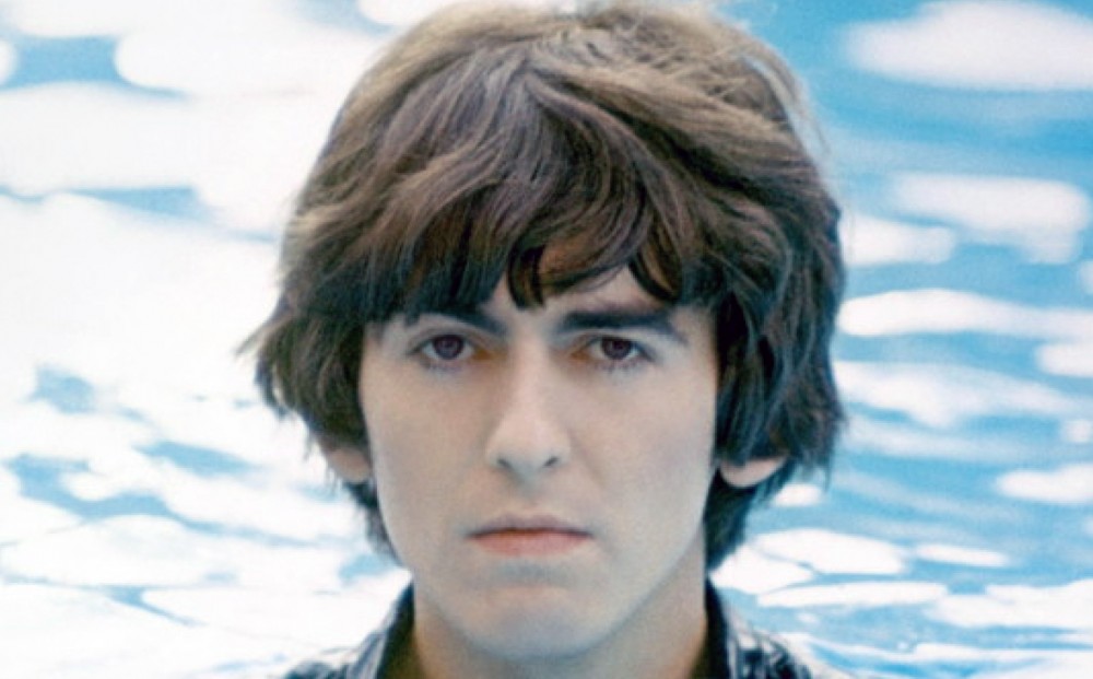 Close-up on George Harrison's face; the water of the pool in which he stands is in the background.
