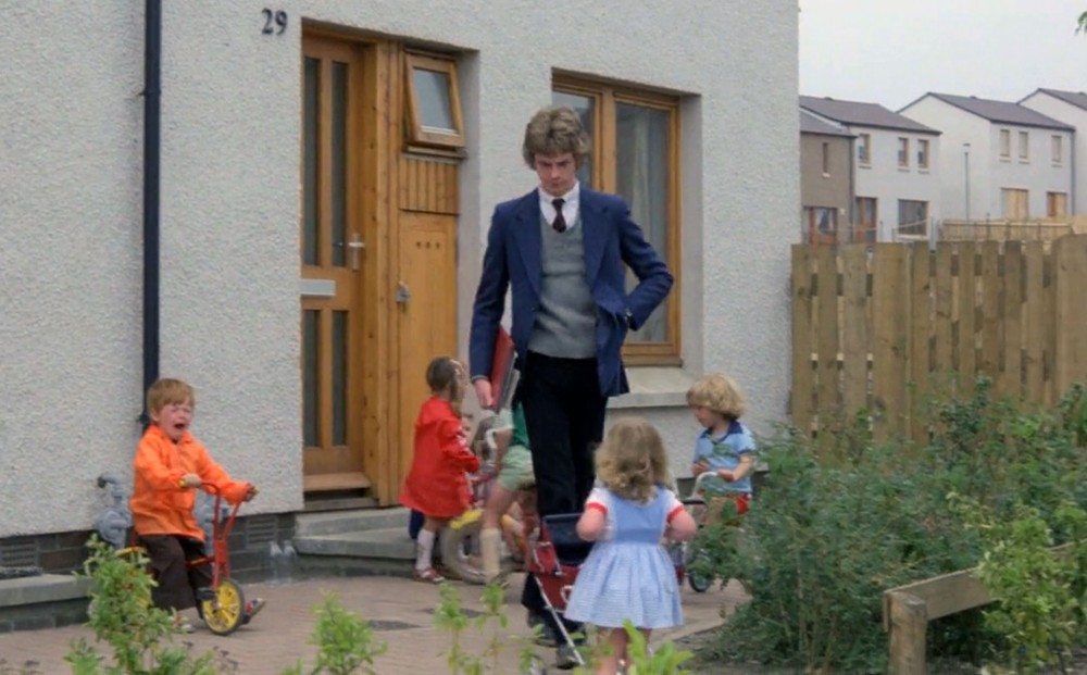 Actor John Gordon Sinclair leaves a house, surrounded by three toddlers playing.