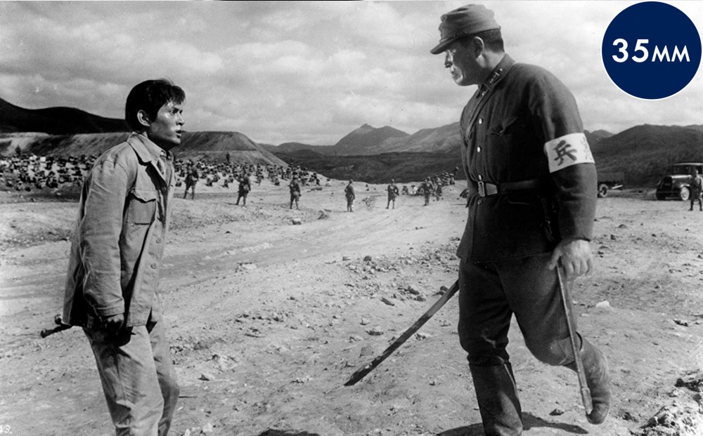 A soldier in uniform approaches actor Tatsuya Nakadai antagonistically. 