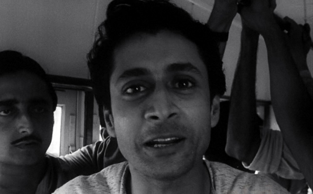 Close-up on the face of Ranjit Mallick who is riding a bus.