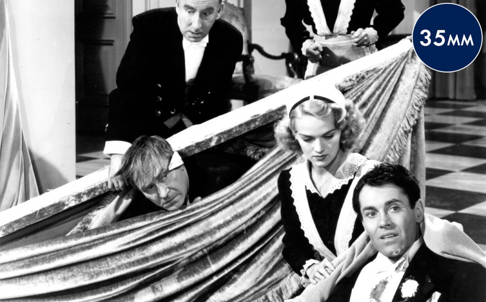 A scene of chaos, as actor Henry Fonda in a groom's tuxedo has fallen, and servants surround him.