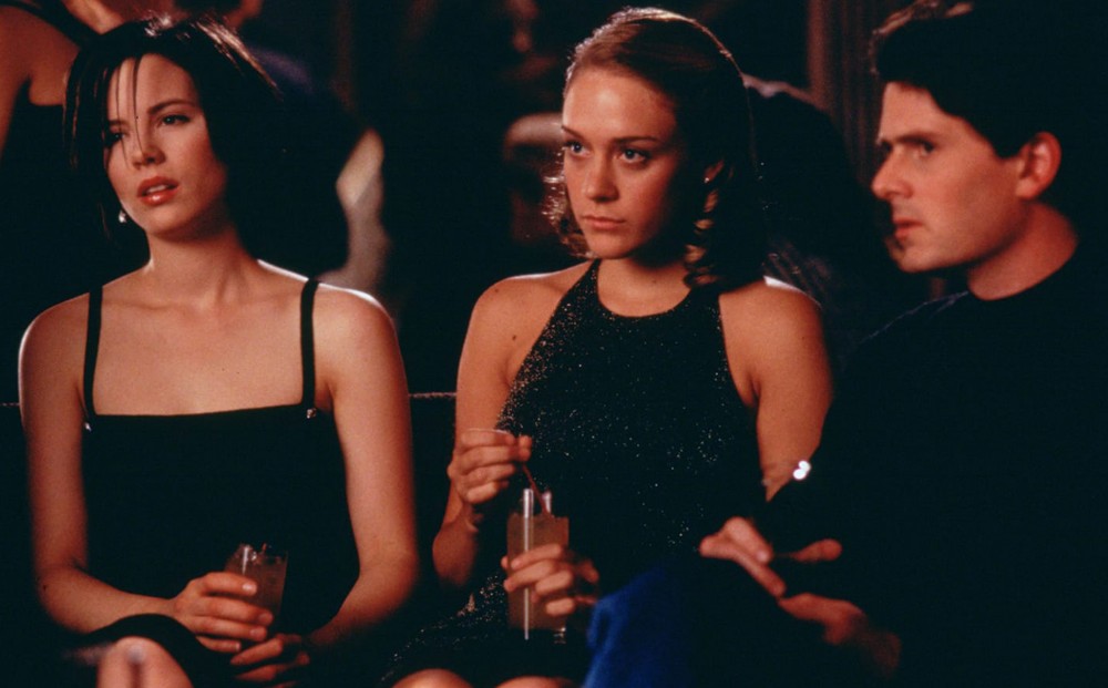 Actors Kate Beckinsale and Chloë Sevigny sit together with a man at a nightclub, holding drinks.