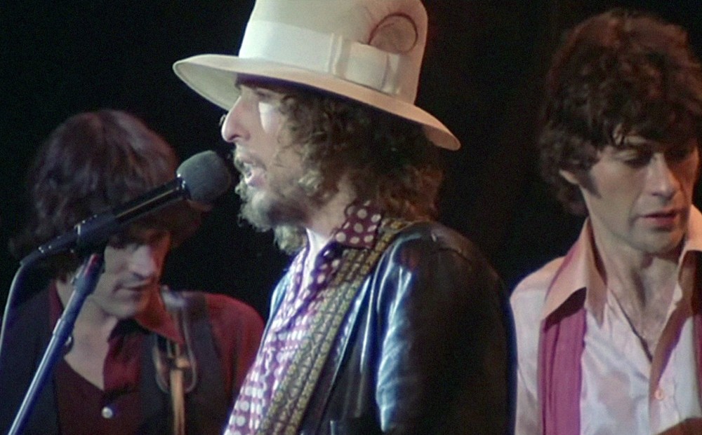 Bob Dylan sings with The Band on-stage.