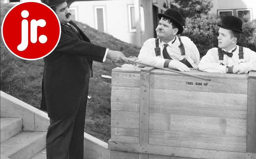 Laurel and Hardy are wheeling away a wooden crate; a man motions towards it angrily with his cane.