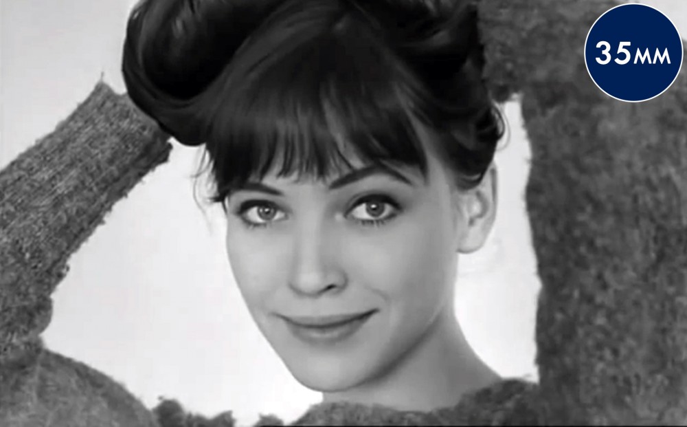 Actor Anna Karina holds her hair on top of her head.