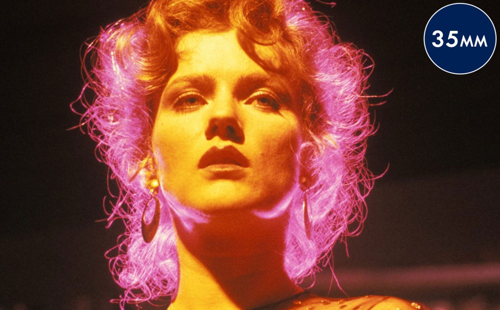 Close-up on actor Barbara Sukowa's face; lit by orange and pink light.