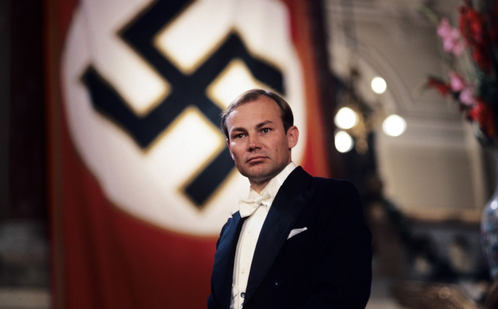 Actor Klaus Maria Brandauer wears a tuxedo; a Nazi flag is in the background.