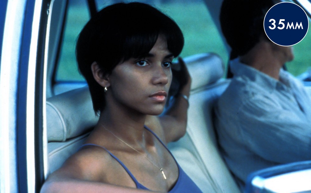 Halle Berry looks out a car window from the passenger seat.