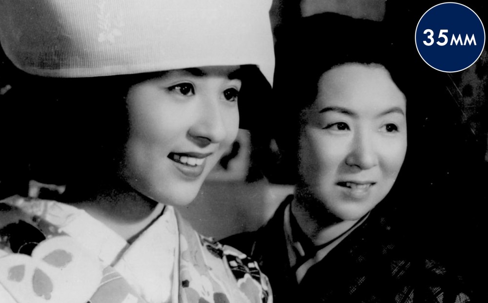 Close-up on the faces of two women who look in the same direction and smile.