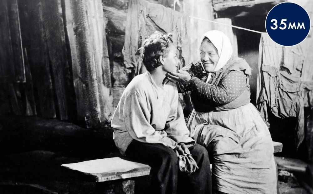 An old woman touches a young boy's face encouragingly.