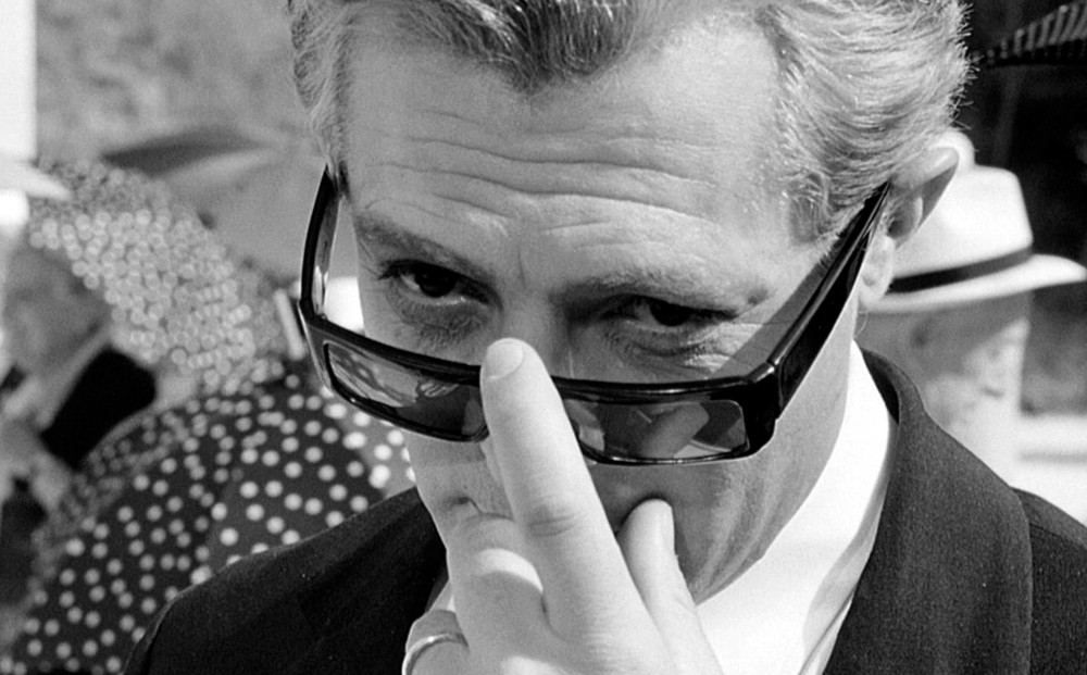 Black and white image of Martin Scorsese peering over his dark sunglasses.