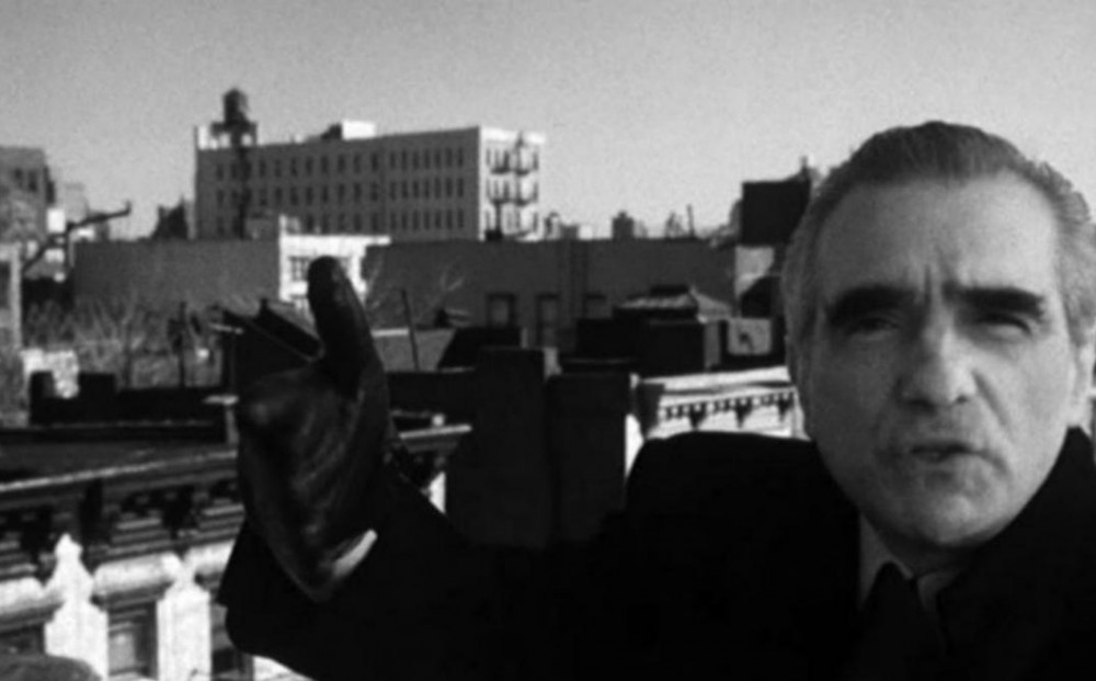 Black and white image of Martin Scorsese motioning towards and speaking to the camera.