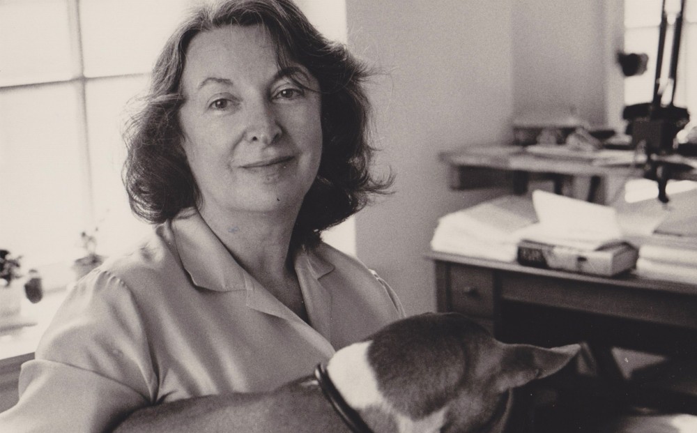 Photograph of Pauline Kael, holding a dog and looking at the camera.