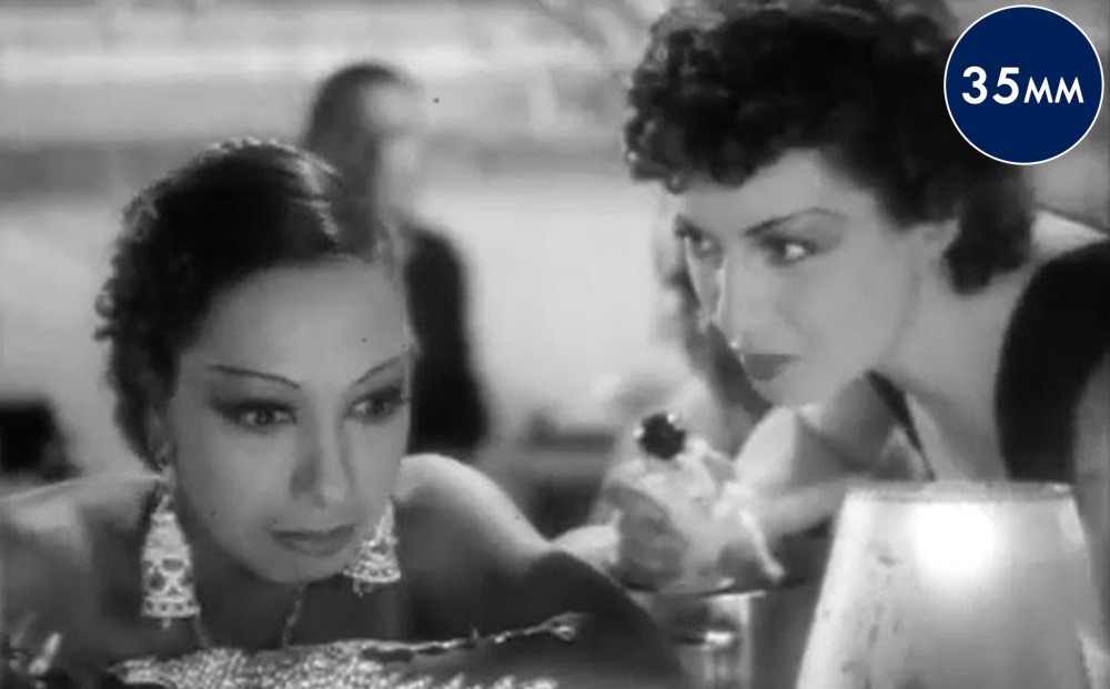 Another woman looks intently at Josephine Baker, who is seated and looking forward.