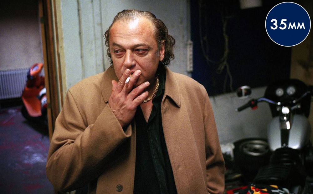 Actor Zlatko Buric smokes a cigarette in a room.