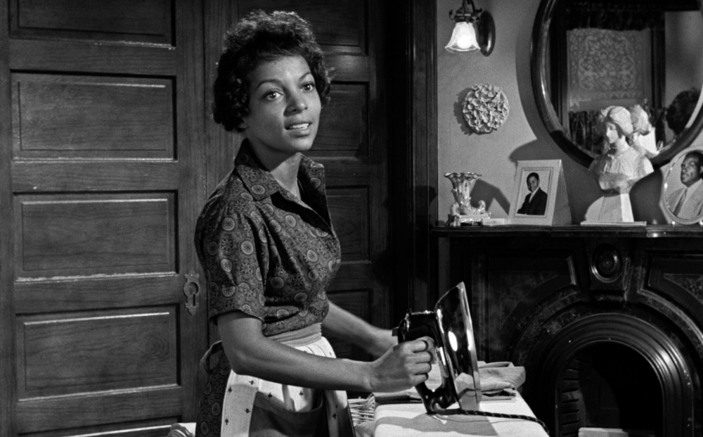 Actor Ruby Dee stands by an ironing table, holding an iron.