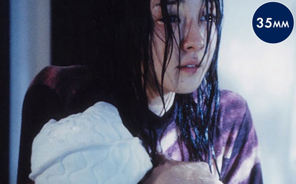 Close-up on a woman with wet hair, clutching something to her chest. 