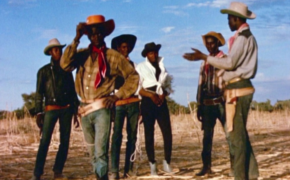 From Le Retour d’un Aventurier: six men stand in a field, wearing cowboy outfits.