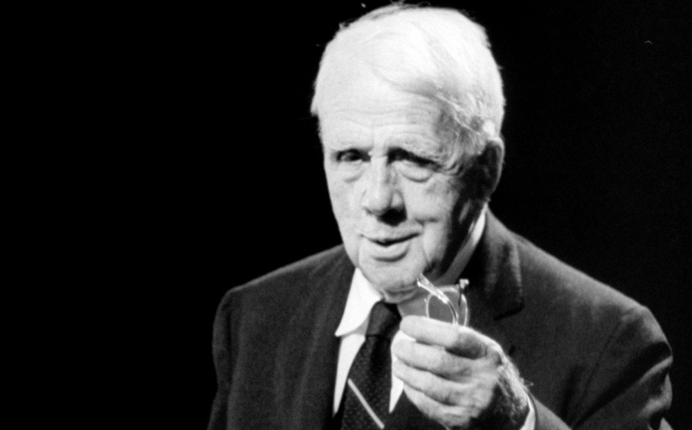 Robert Frost, holding his glasses.