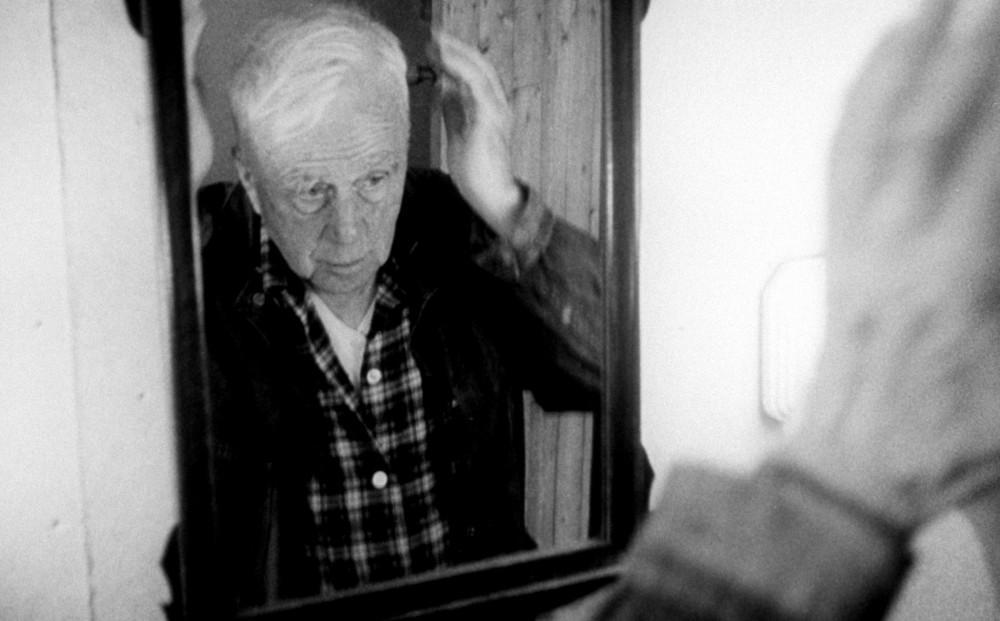 Robert Frost looks at his reflection in a mirror.