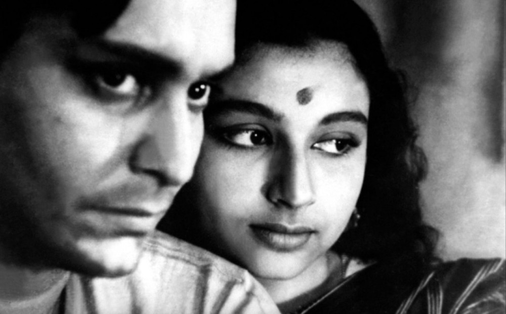 Close-up on the faces of actors Sharmila Tagore and Soumitra Chatterjee.