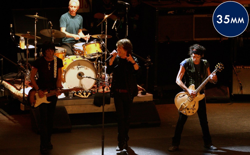 The Rolling Stones perform on stage - two guitarists, a singer, and a drummer.
